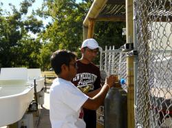 Image of ...Mahesh Boddu (left) and Ranjith Rajasegaram (right) attaching the CO2 tank to the Algal Raceway